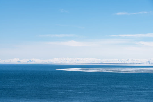 Alpine lake Sevan covered partly by ice on sunny April afternoon