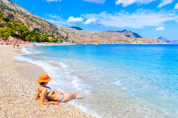 Fototapeta na wymiar Young woman relaxing in water on Apella beach, Karpathos island, Greece