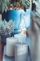 Living room, vase with candles on wooden table, green plant and bokeh on background, selected focus, toned