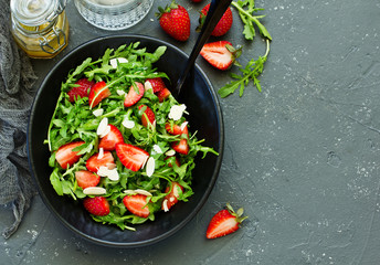 Fresh salad with arugula, strawberries and almonds. Selective focus.