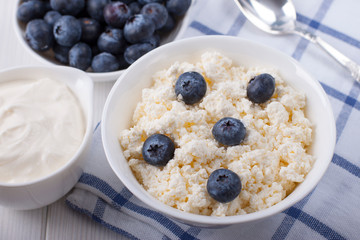 Cottage cheese in a white bowl with berries of fresh blueberries