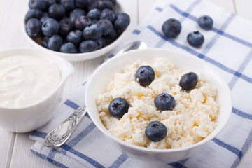 Cottage cheese in a white bowl with berries of fresh blueberries