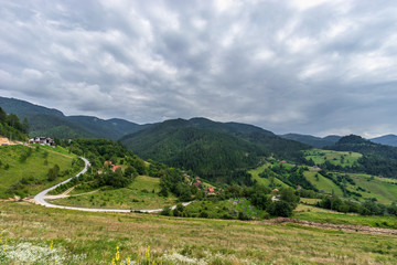 Fototapeta na wymiar View on Lazici village and green hills overgrown with spruce and pine in Serbia in cloudy summer day