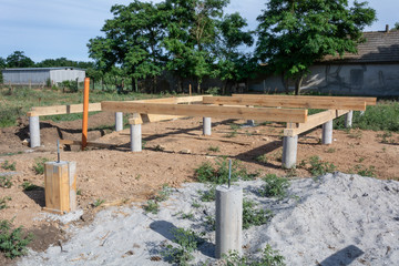 Fototapeta na wymiar Pine wooden frame house foundation on screw piles, construction site. Construction stages of the A-type frame house