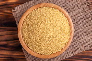 Raw couscous grain in wooden bowl with burlap napkin