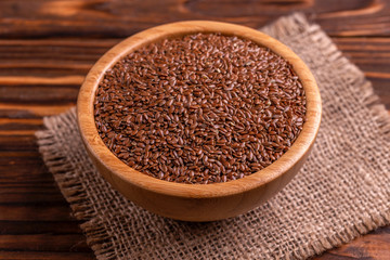 Raw flax seeds in wooden bowl with burlap napkin