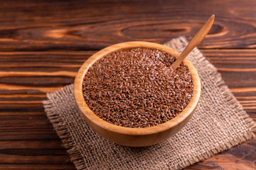 Raw flax seeds in wooden bowl with burlap napkin