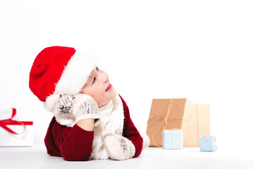 Merry Christmas and happy New year! Cute happy little boy holding present. Kid enjoy holiday with santa hat. Portrait kid on light background isolated. Happy Child with place for text
