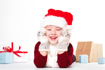 Merry Christmas and happy New year! Cute happy little boy holding present. Kid enjoy holiday with santa hat. Portrait kid on light background isolated. Happy Child with place for text