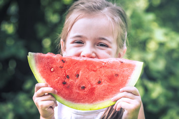 a little girl holding a piece of watermelon
