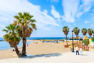 Wall murals Bolonia beach, Tarifa, Spain MARBELLA TOWN, SPAIN - MAY 12, 2018: Couple of tourists walking on coastal promenade along beach in Marbella seaside town. Southern Spain is popular holiday destination in Europe.