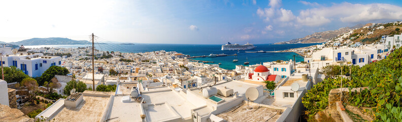 Panoramic view over Mykonos town with white architecture and cruise liner in port, Greece