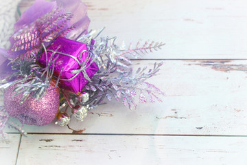 Background new year, Christmas. Christmas decoration, purple branch with balls and gift isolated on gray textured knitted background. Copy space. The festive side.