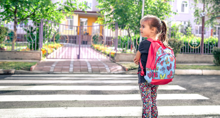 Children go to school, a happy student with a backpack, crosses the road