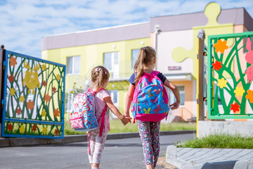 Children go to school, happy students with school backpacks and holding hands together