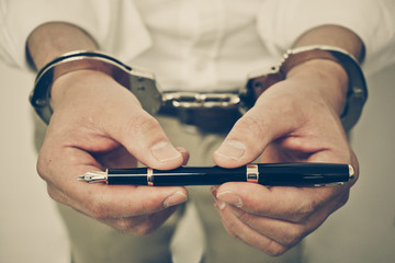 Hand using a pen trying to unlock handcuffs - Freedom of the press is at risk concept - World press...