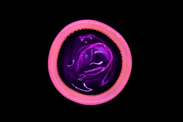 Pink color condom isolated on black background