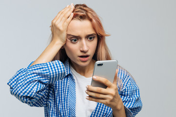 Studio portrait of young cute woman in checked shirt with facepalm gesture, touching head with...