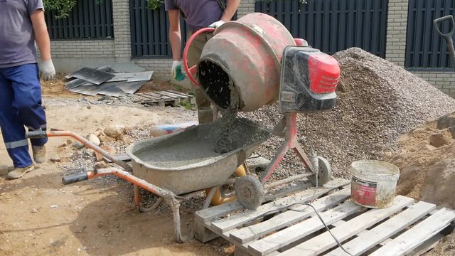 builders unload cement solution out of concrete mixer