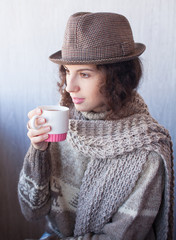 Casual attractive thinking woman holding cup of tea and pensive looking up on white background