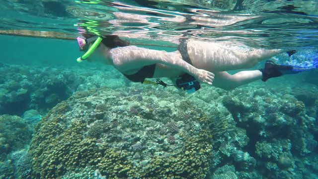 
junge Frau schnorchelt mit Unterwasserkamera an die Riffkante 