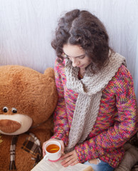 Woman drinking tea and reading book . big teddy bear