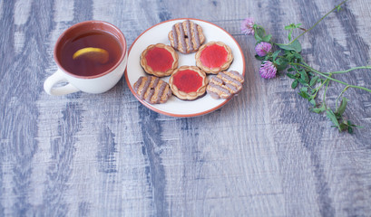 Obraz na płótnie Canvas Cookies in white plate and cup of tea on wooden table, top view.