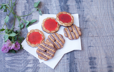 Cookies in white plate and cup of tea on wooden table, top view.