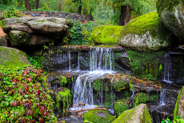 A picturesque cascade waterfall among large moss covered stones in the landscape Sophia Park, Uman, Ukraine,  Autumn Sofievsky