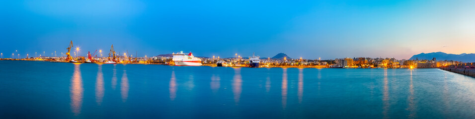 Naklejka na ściany i meble Panorama of Old Venetian Harbour with Lines of Ships and Fishing Boats At Blue Hour in Heraklion City in Greece.