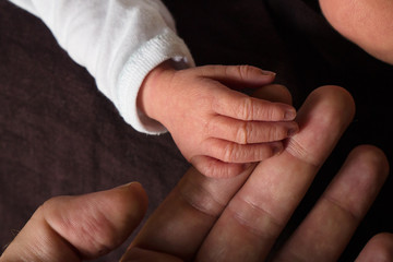 Main de bébé tenant index de son père
