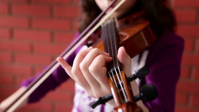 A close up shot of a young girl  practices her violin in classroom