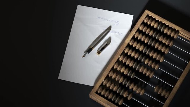 Wooden abacus with handwritten math equations and fountain pen