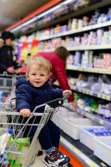 baby sitting in a shopping trolley in a supermarket
