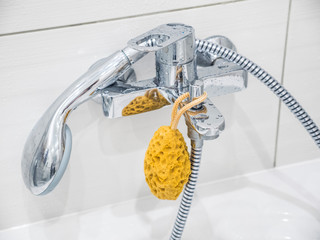 Luxury faucet mixer and white towel on a white sink in a beautiful gray bathroom. Modern silver color stainless steel faucet and water tap in bathroom. Chrome bathroom faucet. Bath yellow rag.
