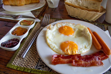 Delicious English Breakfast with fried eggs, sausages, bacon, jam and more