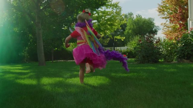 Slow motion tracking shot of girl running wearing fairy wings and waving sword / Pleasant Grove, Utah, United States