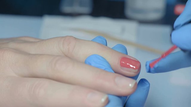 Macro, Manicure Master Deals Red Lacquer Layer on Woman's Fingernail