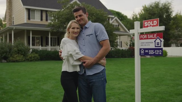 Portrait of proud couple hugging on lawn of sold house for sale / Pleasant Grove, Utah, United States