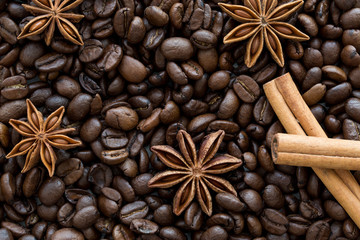 Anise stars and cinnamon sticks on coffee beans background.
