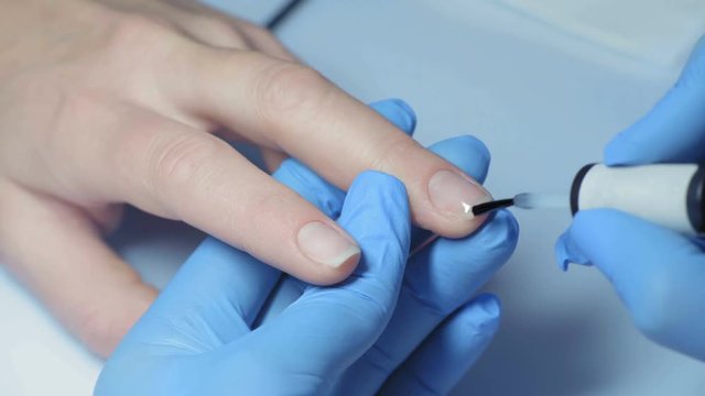 Close-up, Master Manicure Applies a Layer of Protective Varnish on the Girl's Nail