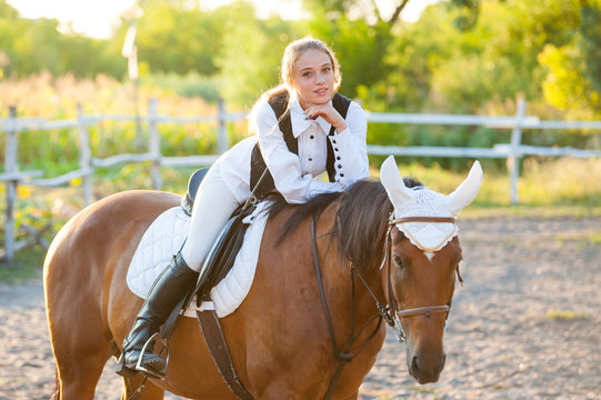 Girl equestrian rider riding a beautiful horse  in the rays of the setting sun. Horse theme