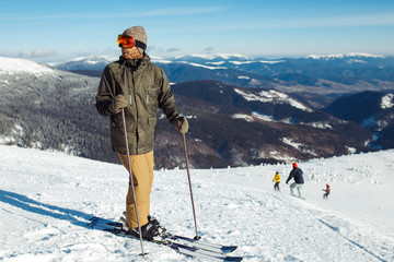 Nice man skiing in the mountains. Good skiing in the snowy mountains,  Winter is coming, first snowfall. Ski resort season is open. Ski equipment, trail. 