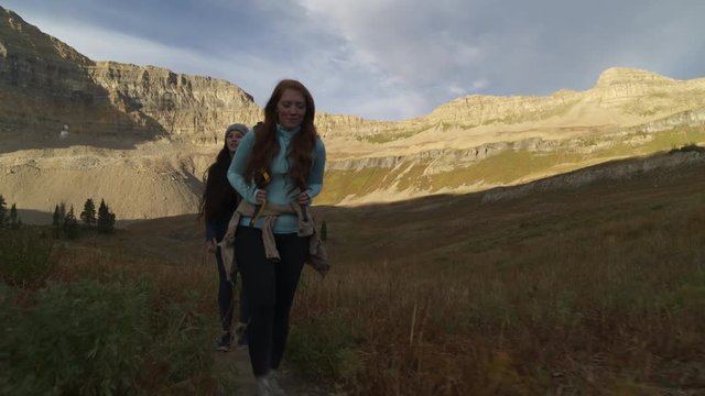 Tracking shot of smiling women hiking on mountain trail / Mount Timpanogos, Utah, United States