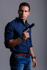 Portrait of serious businessman holding gun while thinking