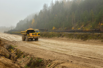 Earth mover loading dumper truck with sand in quarry. Excavator loading sand into dumper...