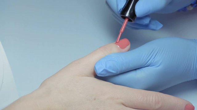 Close-up, Master of Manicure in Gloves Applying Nail on the Nail on the Girl's Hand