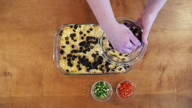 Close up, garnishing 9 layer dip with olives