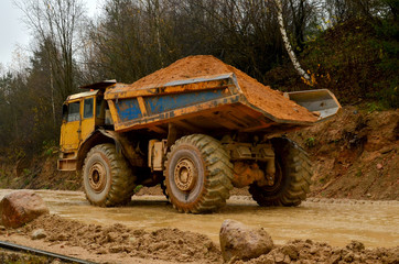 Big yellow diesel truck working in a mining quarry. Heavy mining truck transporting sand and clay. Belaz.