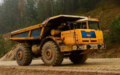 Big yellow diesel quarry dumper at work. Heavy mining truck transporting sand and clay. Belaz.